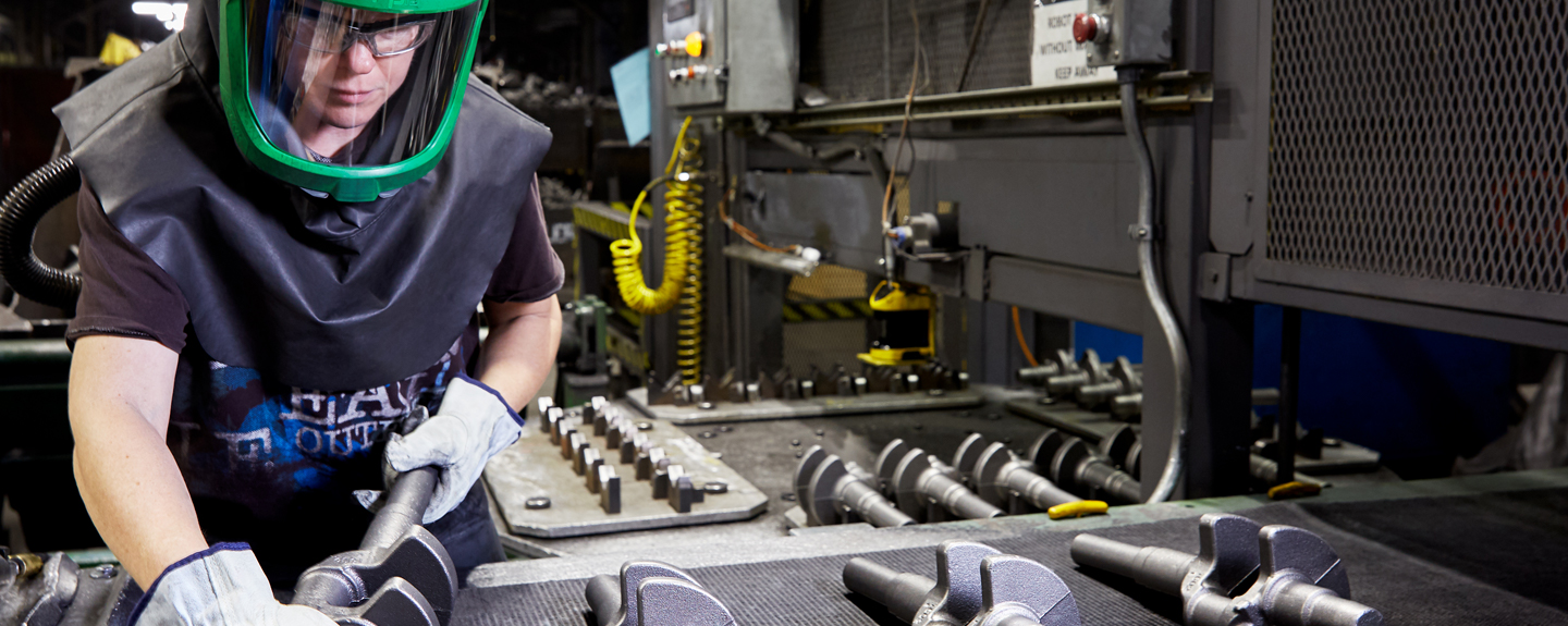 Foundry operator conducting quality assurance checks on cast iron parts post molding 